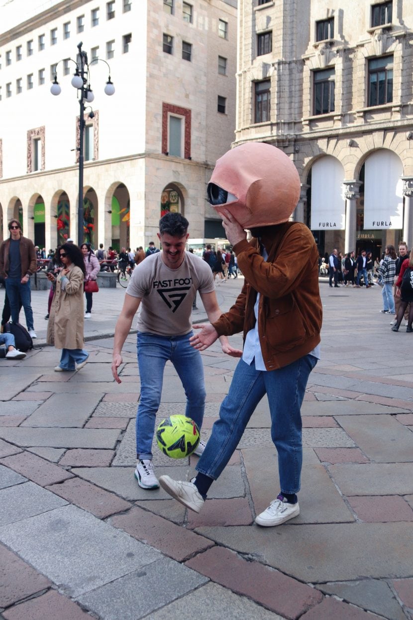 Due ragazzi con in testa la maschera di un grande occhio a Milano.