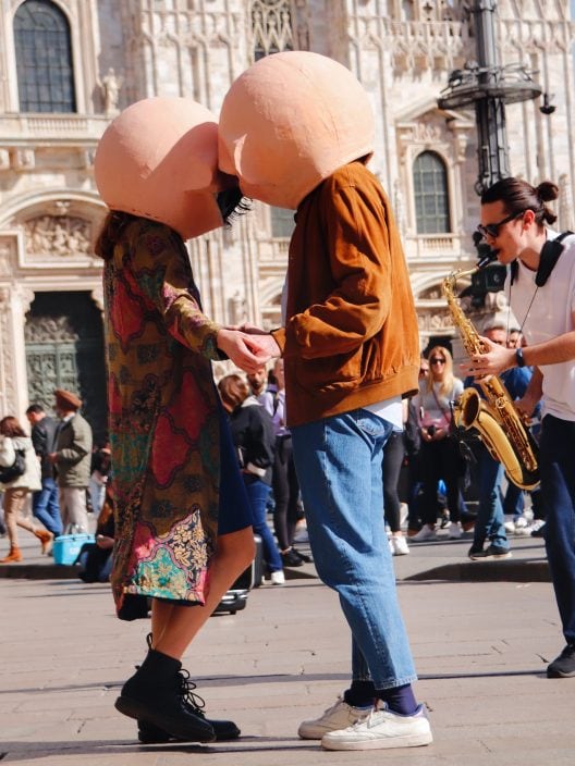 Due ragazzi con in testa la maschera di un grande occhio: il mistero di Milano